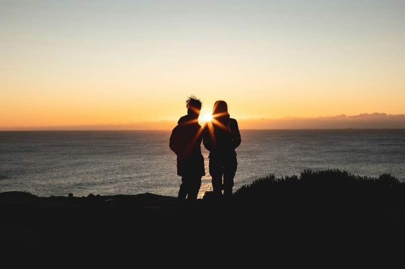 A couple watching the sunset from a hilltop
