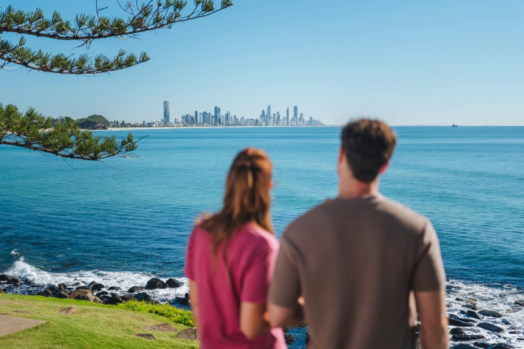 A couple looking out across the ocean to the Gold Coast skyline
